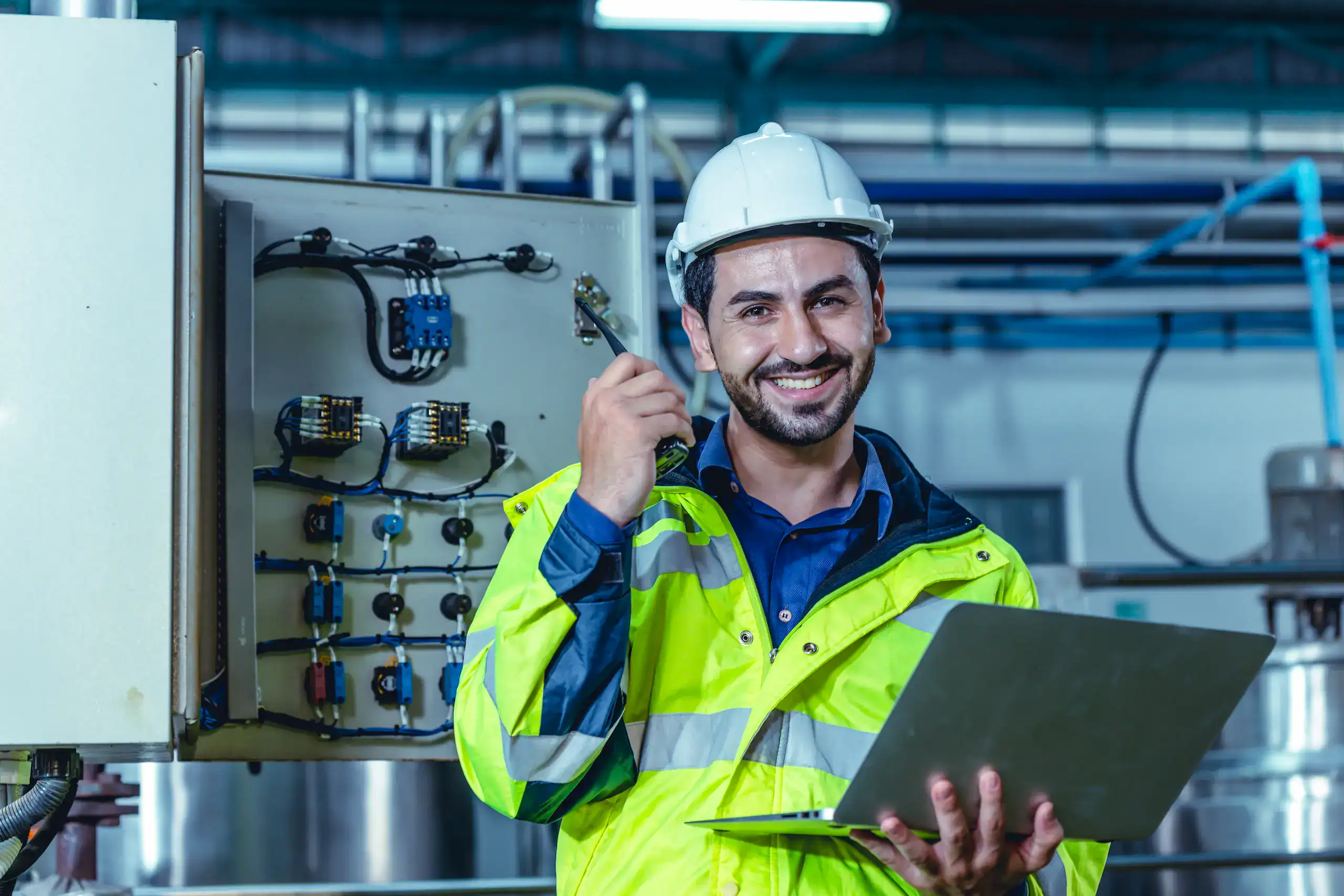 Operarios felices de trabajar de manera segura con protectores contra sobretensiones en ambientes industriales.